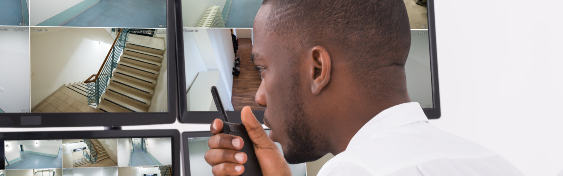 A security personnel looking at a cctv monitor while calling through a radio telephone